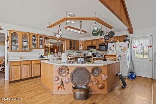 117 Arthur Rd, Beaufort, NC 28516 - kitchen featuring freestanding refrigerator, light wood-style floors, light countertops, a kitchen island with sink, and black microwave