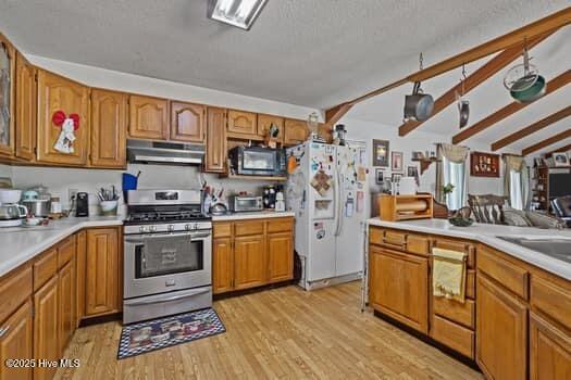 117 Arthur Rd, Beaufort, NC 28516 - kitchen featuring stainless steel range with gas stovetop, white refrigerator with ice dispenser, under cabinet range hood, black microwave, and brown cabinetry