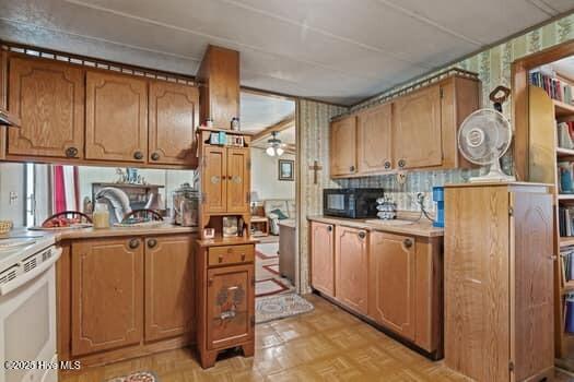 117 Arthur Rd, Beaufort, NC 28516 - kitchen with wallpapered walls, white range with electric cooktop, light countertops, and brown cabinetry