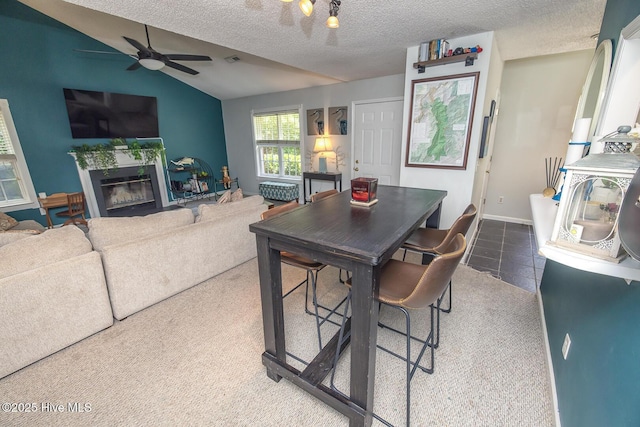 1009 Steeplechase Rd, Wilmington, NC 28412 - dining room with lofted ceiling, a textured ceiling, a ceiling fan, a glass covered fireplace, and baseboards