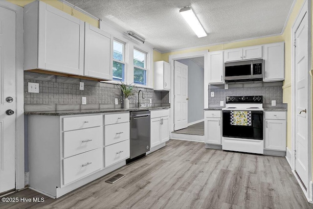 1912 Nun St, Wilmington, NC 28403 - kitchen featuring appliances with stainless steel finishes, white cabinetry, light wood-style floors, backsplash, and a textured ceiling