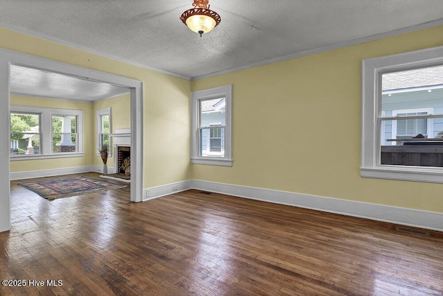 1912 Nun St, Wilmington, NC 28403 - unfurnished room featuring hardwood / wood-style flooring, baseboards, a textured ceiling, ornamental molding, and a fireplace with raised hearth