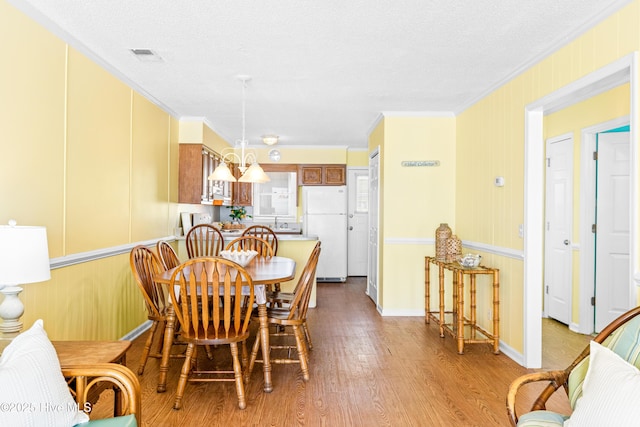 28 E First St Unit 4B, Ocean Isle Beach, NC 28469 - dining area with wood finished floors, ornamental molding, a textured ceiling, and baseboards