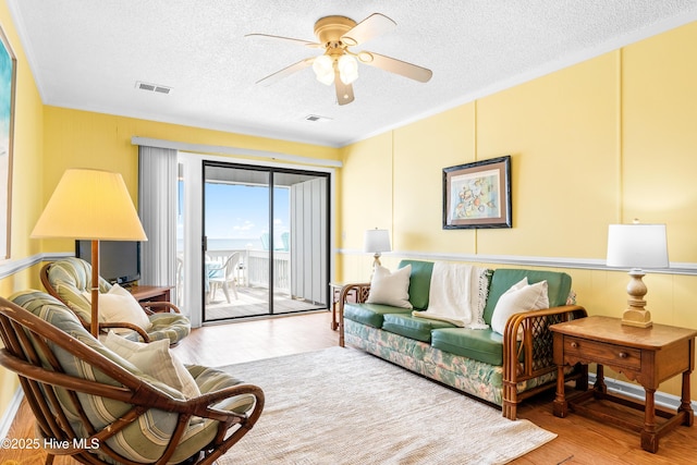 28 E First St Unit 4B, Ocean Isle Beach, NC 28469 - living area with a textured ceiling, wood finished floors, a ceiling fan, and ornamental molding