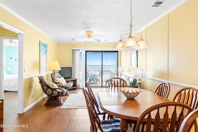 28 E First St Unit 4B, Ocean Isle Beach, NC 28469 - dining room with a ceiling fan, wood finished floors, crown molding, a textured ceiling, and a decorative wall