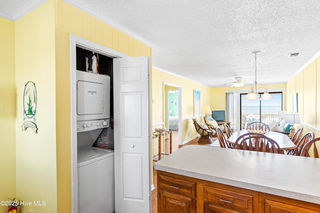 28 E First St Unit 4B, Ocean Isle Beach, NC 28469 - washroom with estacked washer and dryer, ornamental molding, a textured ceiling, a ceiling fan, and baseboards