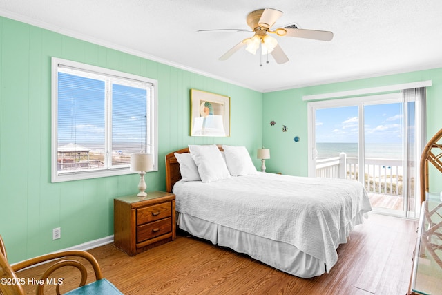 28 E First St Unit 4B, Ocean Isle Beach, NC 28469 - bedroom featuring access to exterior, crown molding, wood finished floors, a water view, and baseboards