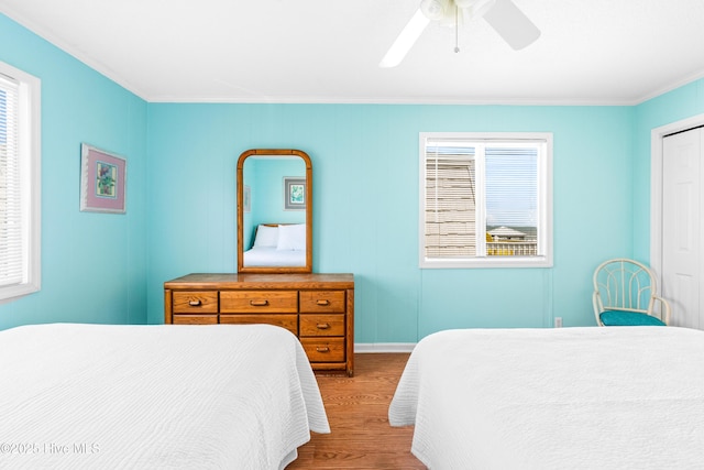 28 E First St Unit 4B, Ocean Isle Beach, NC 28469 - bedroom featuring wood finished floors, ornamental molding, multiple windows, a ceiling fan, and baseboards