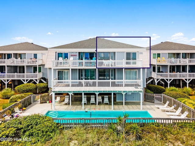 28 E First St Unit 4B, Ocean Isle Beach, NC 28469 - rear view of property with a patio, a community pool, roof with shingles, and fence