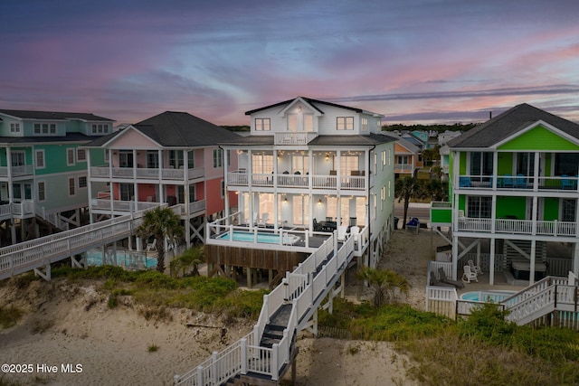 2721 W Beach Dr, Oak Island, NC 28465 - back of house featuring stairway, an outdoor pool, and a residential view