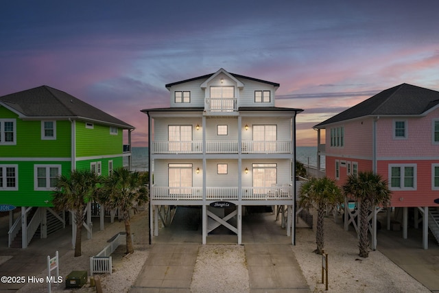 2721 W Beach Dr, Oak Island, NC 28465 - back of property at dusk featuring a carport, a balcony, and driveway