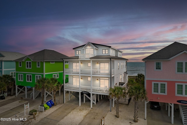 2721 W Beach Dr, Oak Island, NC 28465 - back of property at dusk featuring a carport, a balcony, and a water view