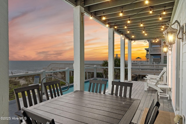 2721 W Beach Dr, Oak Island, NC 28465 - deck at dusk featuring outdoor dining space, a fenced backyard, and a water view