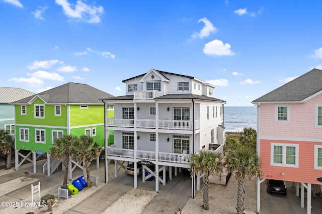 2721 W Beach Dr, Oak Island, NC 28465 - rear view of house featuring a carport, a balcony, a water view, and concrete driveway