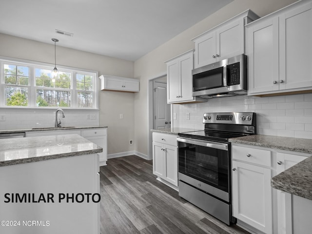 kitchen with stainless steel appliances, a sink, decorative backsplash, and white cabinetry