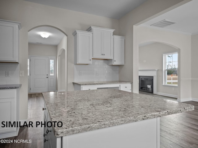 kitchen featuring wood finished floors, light stone countertops, and ornamental molding