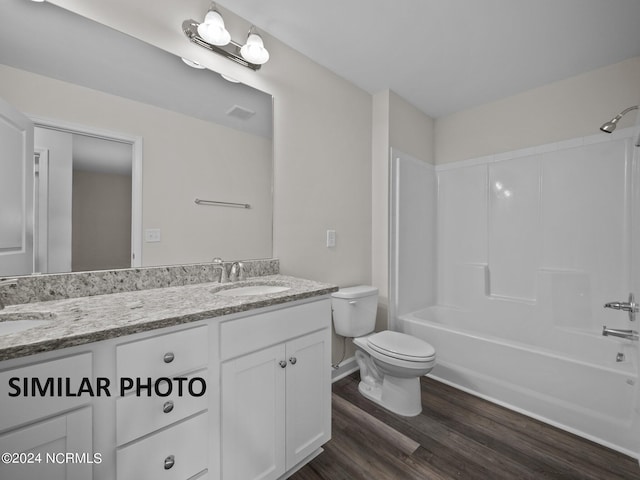 full bathroom featuring toilet, wood finished floors, double vanity, and bathtub / shower combination