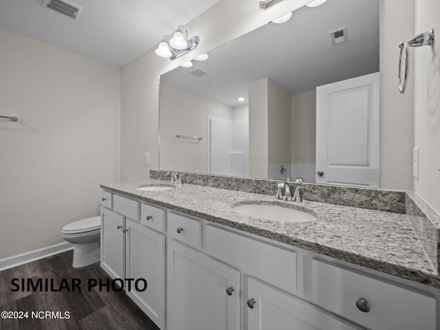full bathroom with toilet, wood finished floors, baseboards, and double vanity