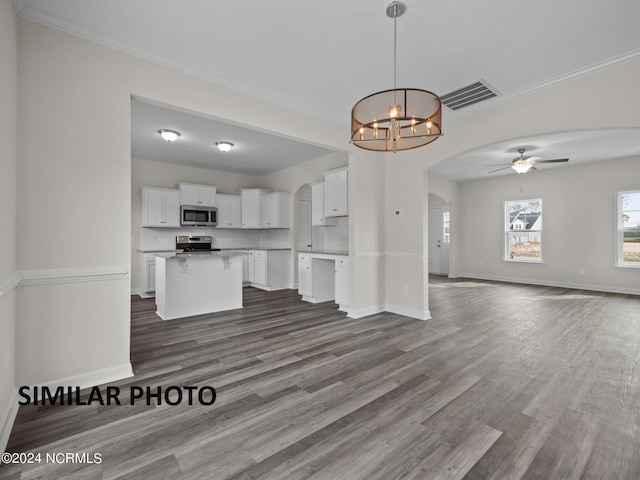 unfurnished living room with arched walkways, ceiling fan, crown molding, dark wood finished floors, and baseboards