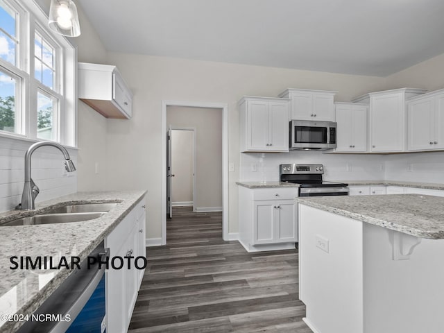 kitchen featuring stainless steel appliances, a sink, white cabinetry, tasteful backsplash, and dark wood-type flooring