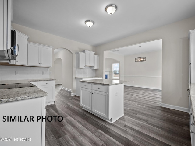 kitchen with arched walkways, tasteful backsplash, white cabinetry, dark wood-style floors, and baseboards