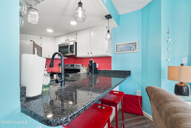 2000 New River Inlet Rd Unit 2501, North Topsail Beach, NC 28460 - kitchen featuring stainless steel appliances, dark wood-style flooring, a peninsula, white cabinetry, and dark stone counters