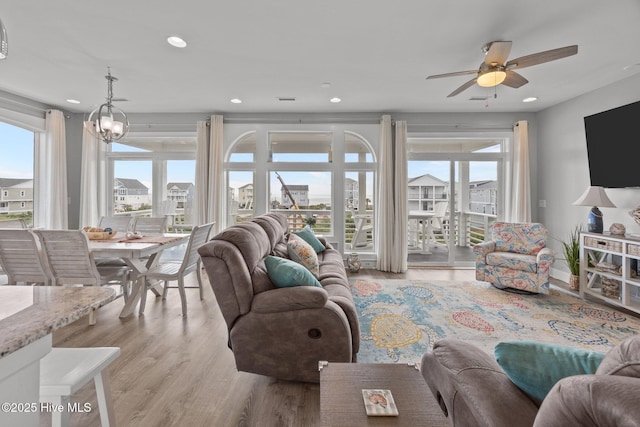 living room with a ceiling fan, light wood-type flooring, recessed lighting, and a chandelier