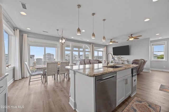 kitchen with a sink, open floor plan, stainless steel dishwasher, light wood-type flooring, and recessed lighting