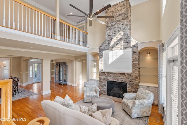 1109 Rollingwood Ct, Leland, NC 28451 - living room with arched walkways, a fireplace, a high ceiling, ceiling fan, and light wood-type flooring