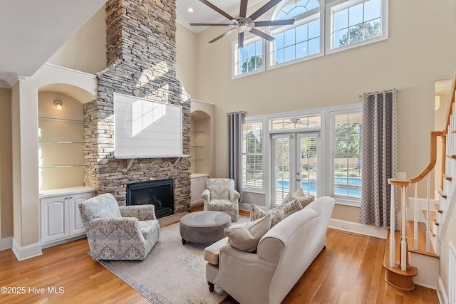 1109 Rollingwood Ct, Leland, NC 28451 - living room featuring light wood-style flooring, a towering ceiling, stairway, a stone fireplace, and baseboards