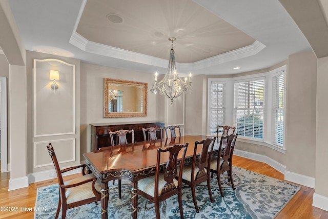 1109 Rollingwood Ct, Leland, NC 28451 - dining room featuring a tray ceiling, ornamental molding, a chandelier, light wood-style floors, and baseboards