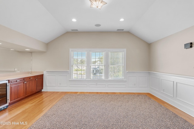 1109 Rollingwood Ct, Leland, NC 28451 - indoor bar with light wood-type flooring, a wainscoted wall, vaulted ceiling, beverage cooler, and recessed lighting
