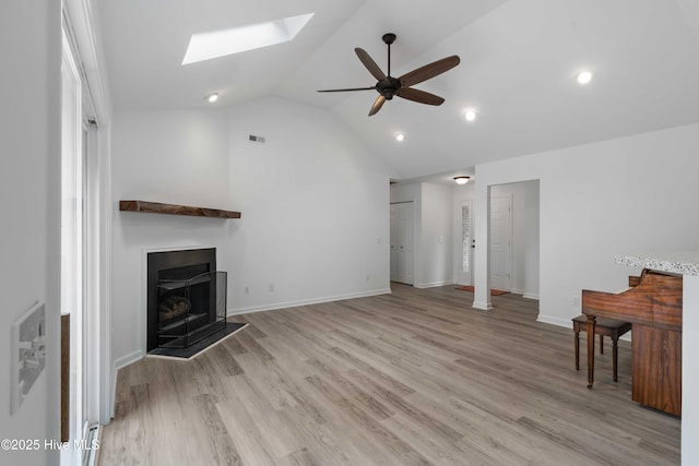 417 Settlers Ln, Kure Beach, NC 28449 - unfurnished living room with a skylight, a ceiling fan, vaulted ceiling, a fireplace, and light wood-style floors