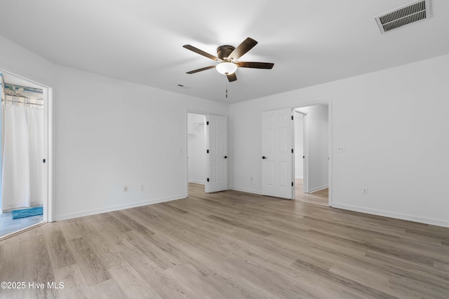417 Settlers Ln, Kure Beach, NC 28449 - unfurnished bedroom with light wood finished floors, baseboards, a ceiling fan, and a walk in closet