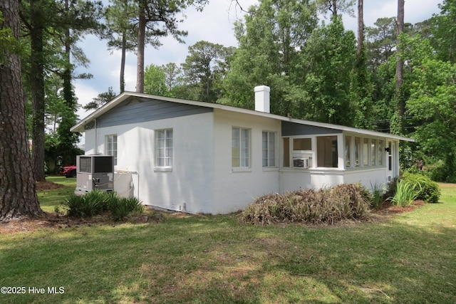 view of property exterior with a lawn, a chimney, central air condition unit, and stucco siding