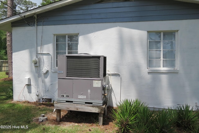 view of side of home with central AC unit and stucco siding