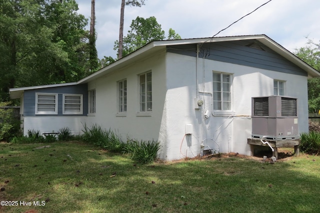view of side of home featuring a lawn, stucco siding, and cooling unit