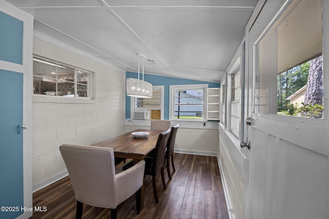 dining room with dark wood-style floors, concrete block wall, cooling unit, and vaulted ceiling
