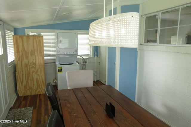 dining area with dark wood finished floors, estacked washer and dryer, and lofted ceiling