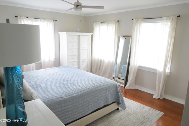 bedroom with wood finished floors, baseboards, crown molding, and a ceiling fan