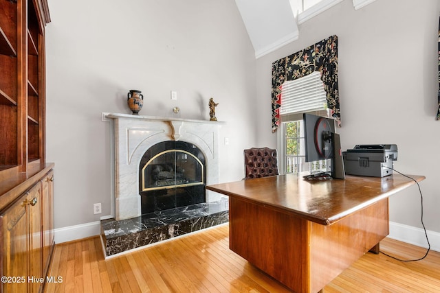 living area featuring baseboards, hardwood / wood-style flooring, a high end fireplace, and high vaulted ceiling