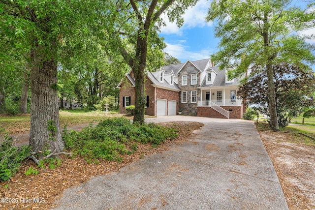 view of front of home featuring concrete driveway, a garage, covered porch, stairway, and brick siding