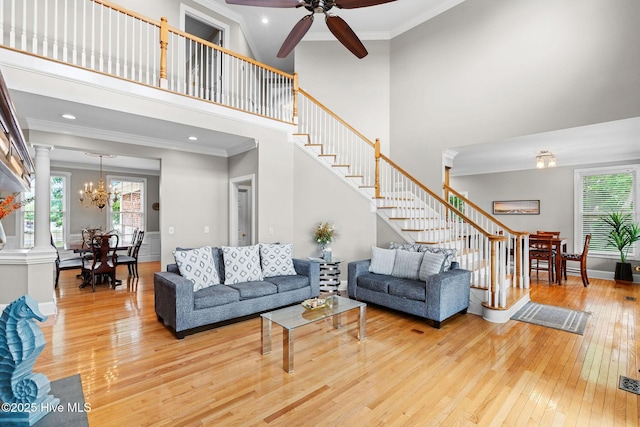living room featuring hardwood / wood-style flooring, stairway, healthy amount of natural light, a towering ceiling, and crown molding