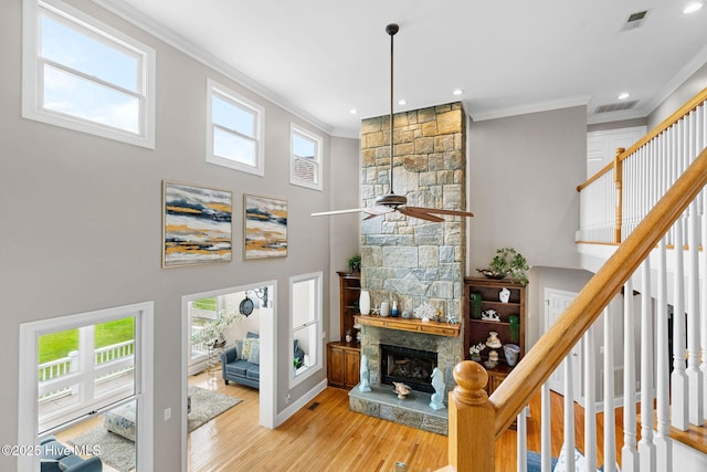 living area featuring ornamental molding, a fireplace, ceiling fan, wood finished floors, and stairs