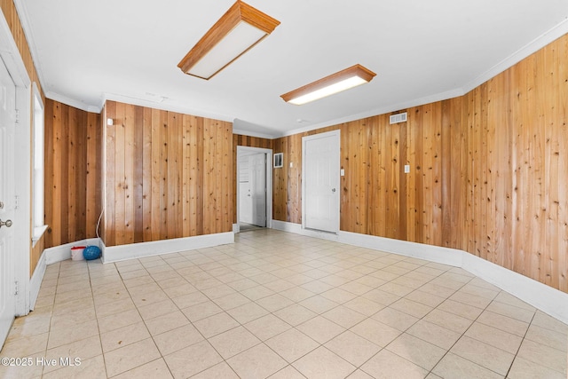 empty room featuring ornamental molding, wooden walls, and baseboards