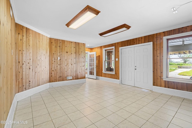 entrance foyer featuring wooden walls, ornamental molding, baseboards, and tile patterned floors