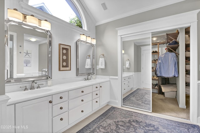 full bath featuring ornamental molding, double vanity, wainscoting, a spacious closet, and tile patterned floors