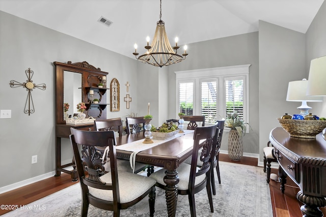 dining space featuring a chandelier, wood finished floors, high vaulted ceiling, and baseboards