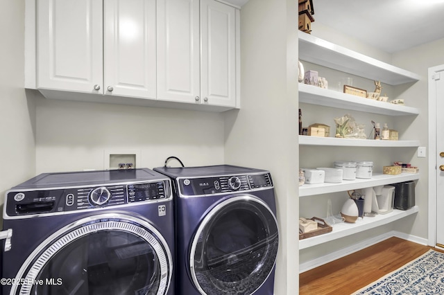 laundry room featuring washing machine and clothes dryer, wood finished floors, and cabinet space