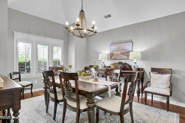 dining space with a chandelier, baseboards, wood finished floors, and high vaulted ceiling
